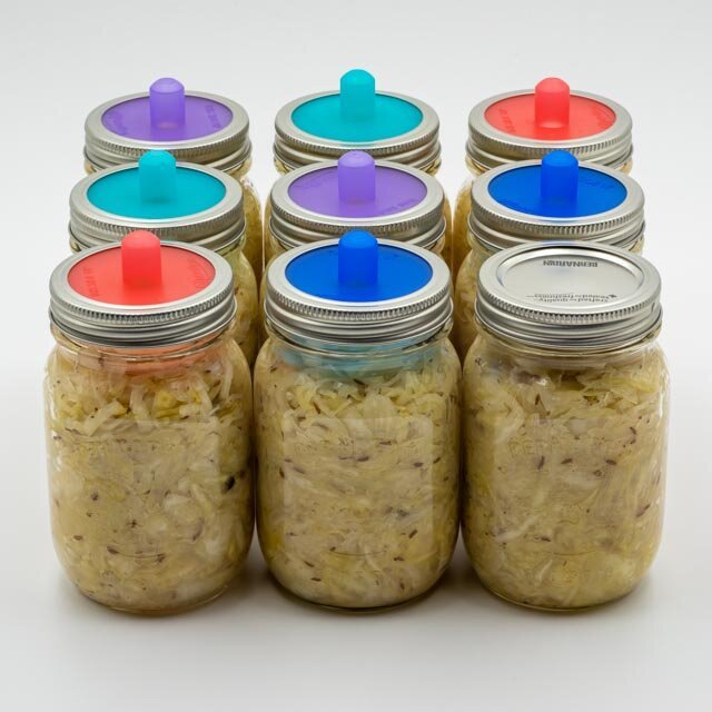 Jars of sauerkraut with lids that allow fermentation gasses to escape.